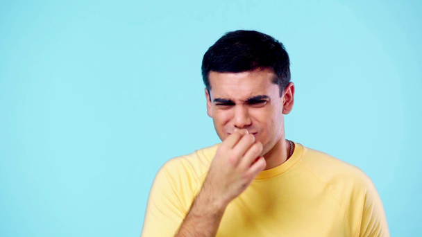 niezadowolony człowiek machający ręką i zatykający nos od smrodu odizolowanego na niebiesko - Materiał filmowy, wideo