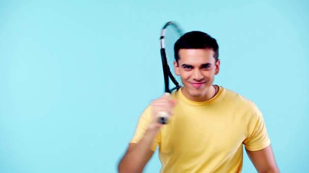 szczęśliwy człowiek gospodarstwa rakieta tenisowa izolowane na niebieski - Materiał filmowy, wideo