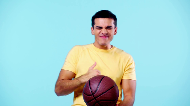 Aufgeregter Sportfan mit Basketball zeigt Siegergeste auf blauem Grund - Filmmaterial, Video