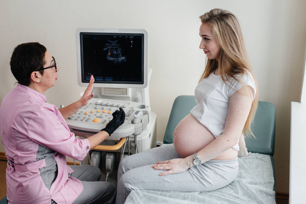 Un médico aconseja a una niña embarazada después de una ecografía en la clínica. Examen médico - Foto, Imagen
