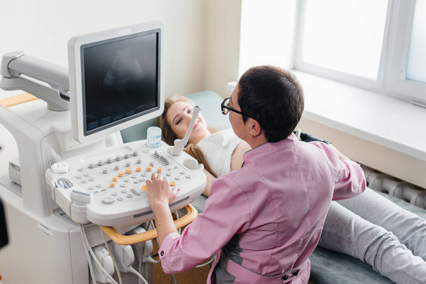 A pregnant girl gets an ultrasound of her abdomen at the clinic. Medical examination - 写真・画像