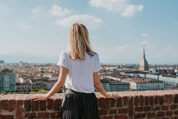 Blonde woman enjoy panorama of the Turin. Amazing scenic view on Mole Antonelliana. Girl explore Piemonte, Italy. Town and mountain. Cityscape, old historic architecture. Travel, adventure, lifestyle - Foto, Imagen