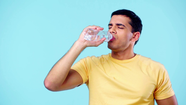 Mann leidet unter Hitze, trinkt, zeigt wie und lächelt isoliert auf blauem Grund - Filmmaterial, Video
