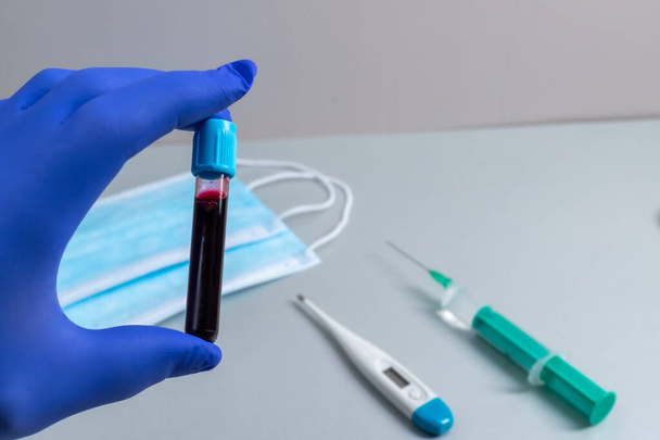Mano de un médico sosteniendo una botella de muestra de sangre - Foto, imagen