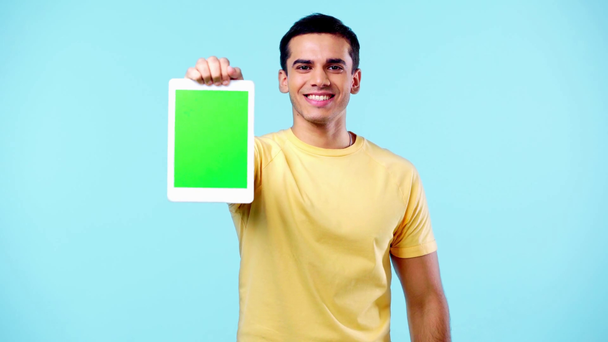 щасливий чоловік показує цифровий планшет з зеленим екраном ізольовано на синьому
 - Кадри, відео