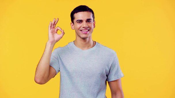 joyful man showing okay sign and smiling at camera isolated on yellow - Metraje, vídeo