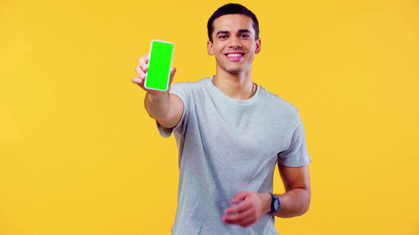 улыбающийся человек болтает и показывает смартфон изолирован на желтый
 - Кадры, видео