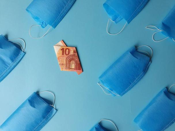 Billete europeo de diez euros y máscaras sobre fondo azul
 - Foto, imagen