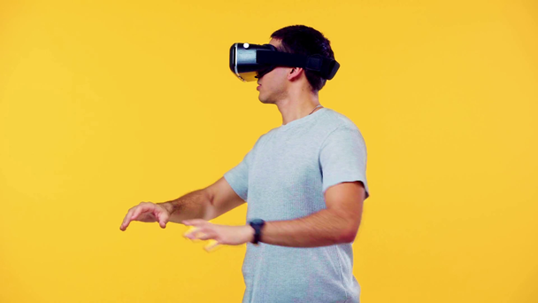 vzrušený muž pomocí vr sluchátka a gestikulace izolované na žluté - Záběry, video