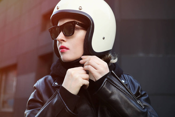Close-up portrait of biker girl adjusting her white helmet. Outdoor.  - Foto, afbeelding