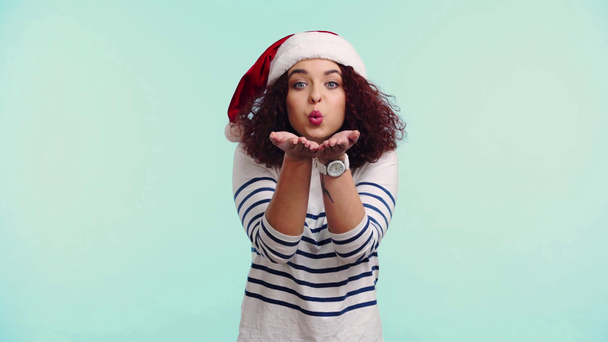 happy curly girl in santa hat blowing air kiss isolated on turquoise - Video, Çekim