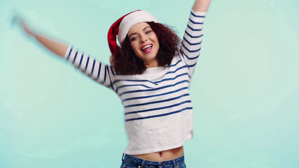 vrolijk meisje in santa hoed zwaaien hand en dansen geïsoleerd op turquoise - Video