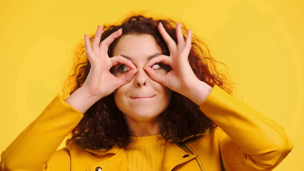 alegre chica imitando gafas con las manos y muecas aislado en amarillo
 - Metraje, vídeo