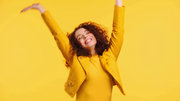 šťastný kudrnatý dívka tanec, zpěv a gestikulace izolované na žluté - Záběry, video