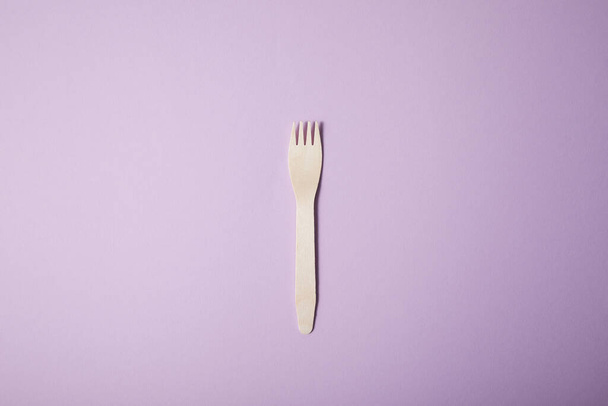 tenedor de madera aislado sobre fondo de papel violeta
 - Foto, Imagen