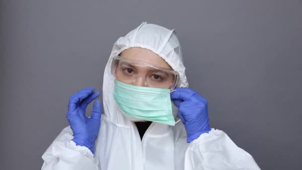 Doctor in protective costume puts on a mask - Materiaali, video