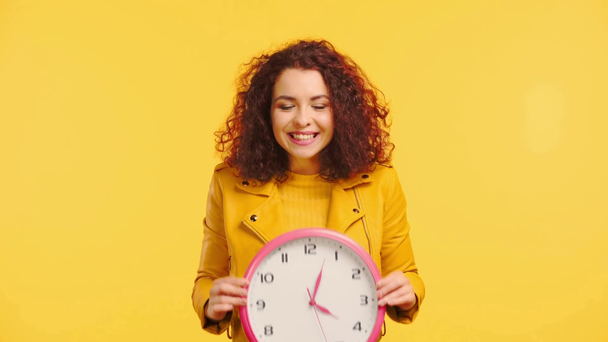 sorridente, mulher complicada obscurecendo rosto com relógio redondo isolado no amarelo
 - Filmagem, Vídeo