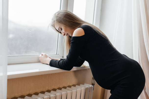 Severe pain in a pregnant woman standing near the window. Pregnancy - Фото, зображення