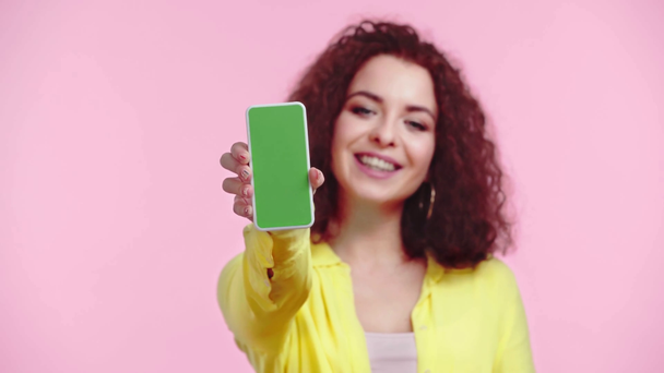 щаслива дівчина, що показує смартфон із зеленим екраном ізольовано на рожевому
 - Кадри, відео
