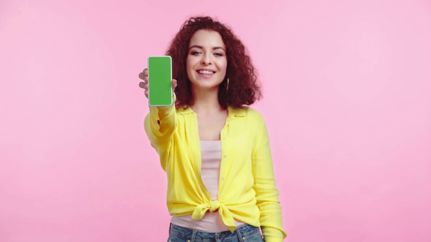 alegre chica mostrando smartphone con pantalla verde aislado en rosa
 - Metraje, vídeo