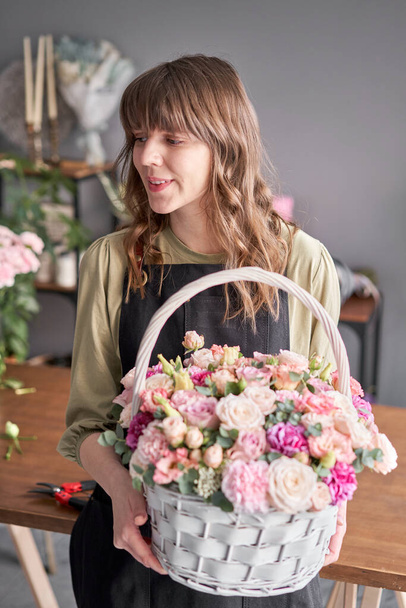 Small flower shop and Flowers delivery. Flower arrangement in Wicker basket. Beautiful bouquet of mixed flowers in woman hand. Handsome fresh bouquet. - Photo, Image