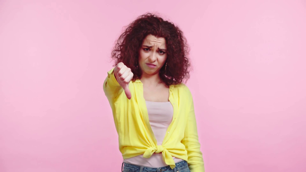 displeased girl showing thumb down while looking at camera isolated on pink - Footage, Video