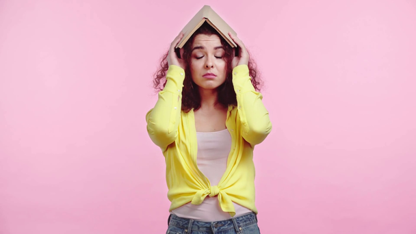 estudiante aburrido cabeza cubierta con libro aislado en rosa
 - Imágenes, Vídeo