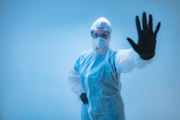 Tıbbi doktor, virüslerden ve hastalıklardan korunmak için giyinmiş bilim adamı elinde dur işareti tutuyor- virüsün yayılmasını engelle. - Fotoğraf, Görsel