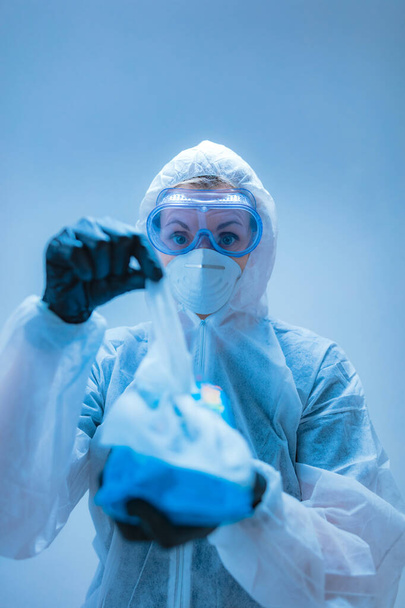 Ιατρός, επιστήμονας σε πλήρη φόρμα σώματος για την πρόληψη από ιούς και ασθένειες που κατέχουν αντισηπτικό ιστό για απολύμανση. - Φωτογραφία, εικόνα