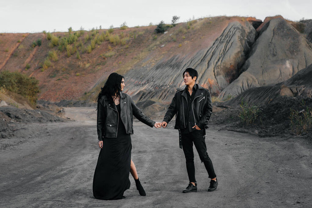 An Asian couple in love in black leather clothes walk in nature among the trees. Style, fashion, love - Фото, зображення