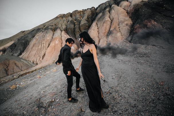 An Asian couple in love lit black smoke bombs in the mountains. Colored smoke - Φωτογραφία, εικόνα