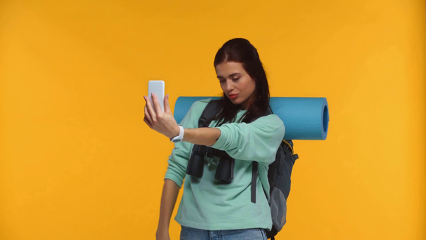 Viajero feliz tomando selfie con smartphone aislado en amarillo
 - Metraje, vídeo
