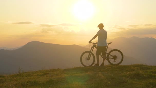 SLOW MOTION: Mladý turista pozoruje krajinu před jízdou na horském kole - Záběry, video