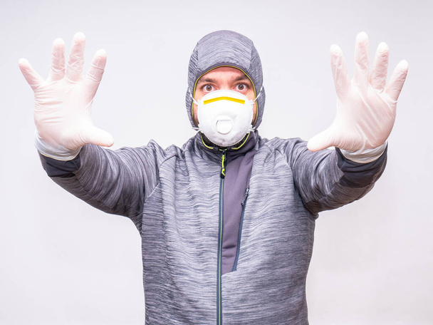 Muž s kapucí a maskou má paže natažené k fotoaparátu rukavicemi jako součást individuálního ochranného vybavení - Fotografie, Obrázek