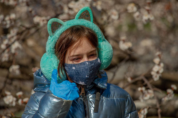 Dışarıdaki koruyucu maskeli kadın. Dışarıdaki maskeli kız. Virüs, maske, bahar. Kız 9 yaşında. Sokak. Virüs ve bakterilere karşı koruma. Tıbbi solunum maskesi. Salgın hastalık. Koruma - Fotoğraf, Görsel