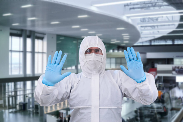 mies epidemiologi coverall kertakäyttöisiä anti-epidemia antibakteerinen eristys puku osoittaa kiellon ele vastaan sisätilojen lentokentälle tai rautatieasemalle
 - Valokuva, kuva