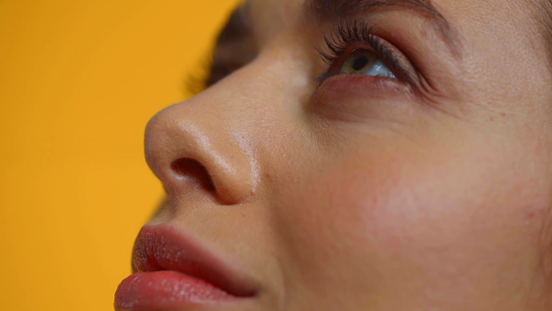 Close up view of beautiful woman looking up isolated on yellow - Imágenes, Vídeo