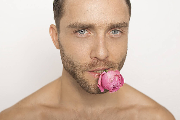 Muscle strong beautiful stripped male model with peony flowers in a vase with water on white isolated font background  - Photo, image
