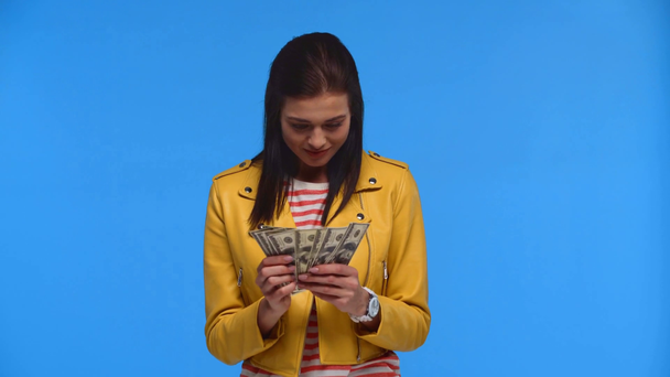Chica alegre contando billetes de dólar aislados en azul
 - Imágenes, Vídeo