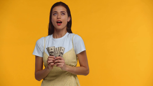 Smiling girl throwing dollar banknotes isolated on yellow - Footage, Video