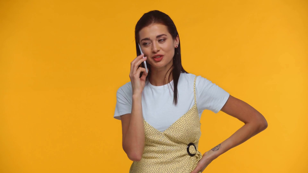 Smiling girl talking on smartphone isolated on yellow - Záběry, video