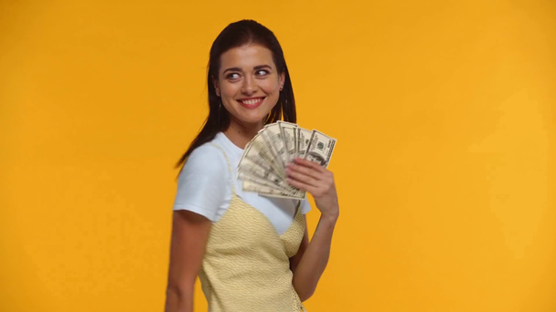 Smiling woman waving dollar banknotes isolated on yellow - Metraje, vídeo