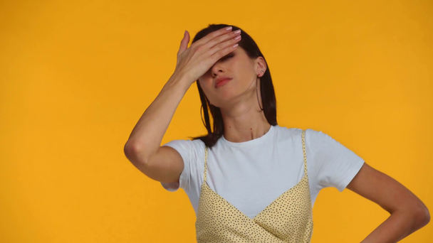 Niezadowolona dziewczyna pokrywa twarz odizolowaną na żółto ręką - Materiał filmowy, wideo