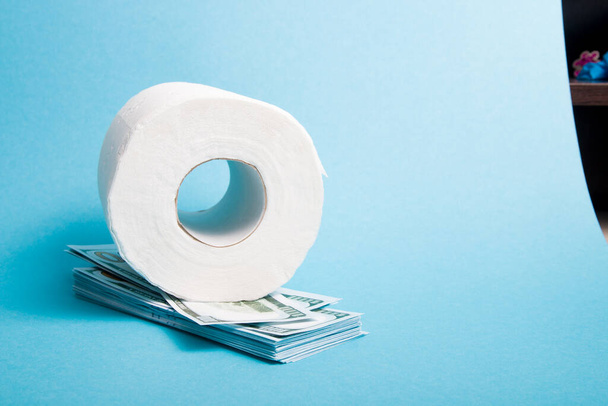 rolki białego papieru toaletowego i stos 100 dolarów banknotów niebieski tło kopia przestrzeń - Zdjęcie, obraz