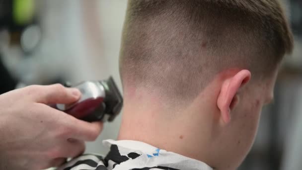 Haircut mladého muže v holičství. Detailní záběr na mistra stříhání vlasů s výstřižkem na zadní straně hlavy - Záběry, video