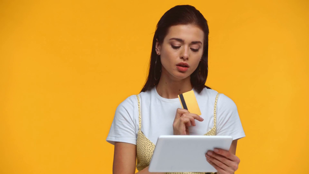 Chica sonriente usando tableta digital y tarjeta de crédito aislada en amarillo
 - Metraje, vídeo