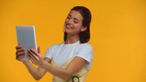 Χαμογελαστό κορίτσι που έχει βιντεοκλήση σε ψηφιακή ταμπλέτα απομονώνονται σε κίτρινο - Πλάνα, βίντεο