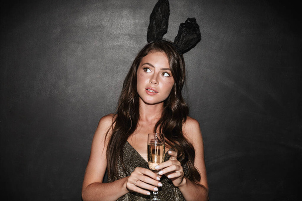Beautiful lovely young girl wearing fancy dress celebrating isolated over black background, drinking champagne - Foto, immagini