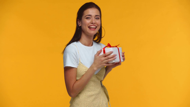 Cheerful girl dancing with gift box isolated on yellow - Filmati, video