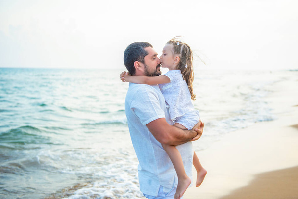 Abrazos suaves y un beso en el mar. Padre amoroso e hija en la costa del mar, familia feliz
. - Foto, Imagen